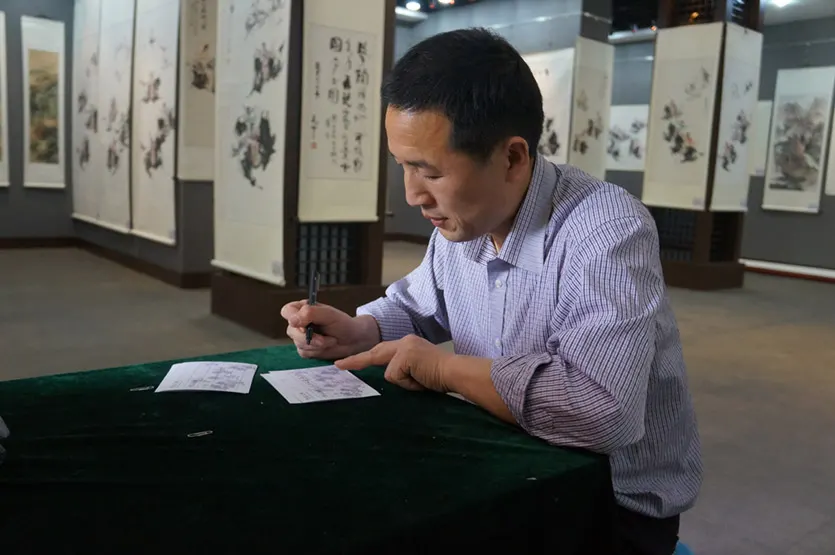 兜底儿网展览部主任、签约书法家子慧黄勇先生在对将要展览的作品填写作品介绍
